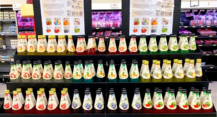 A wide array of 'Mr. Basil' drinks arranged in colorful rows on a store display, with information about the drinks presented on the side.